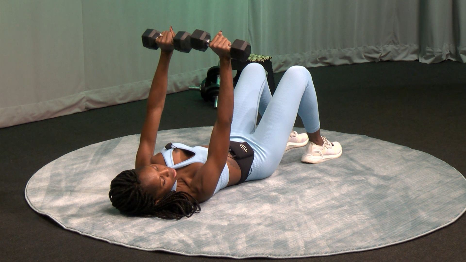 Woman lying down with weights in the air